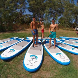 Tres chicos subidos en varias tablas de paddle surf